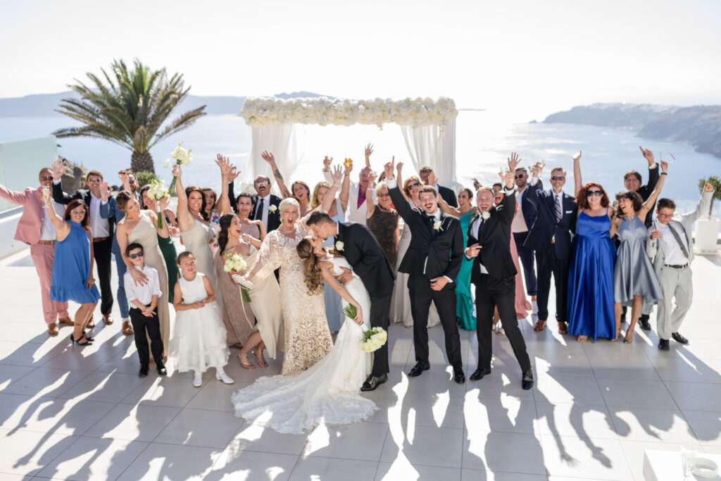 big group of wedding guests celebrating with bride and groom at Santorini wedding at Le Ciel