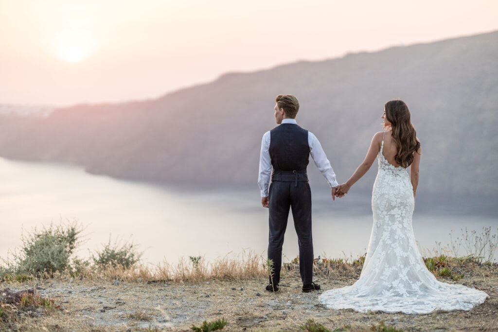 bride and groom watching the sunset at their Santorini wedding at le Ciel