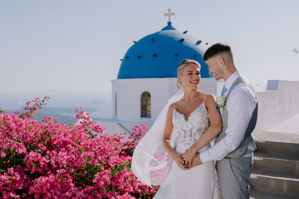 Bride and groom at a destination wedding in Greece in from of blue and white building