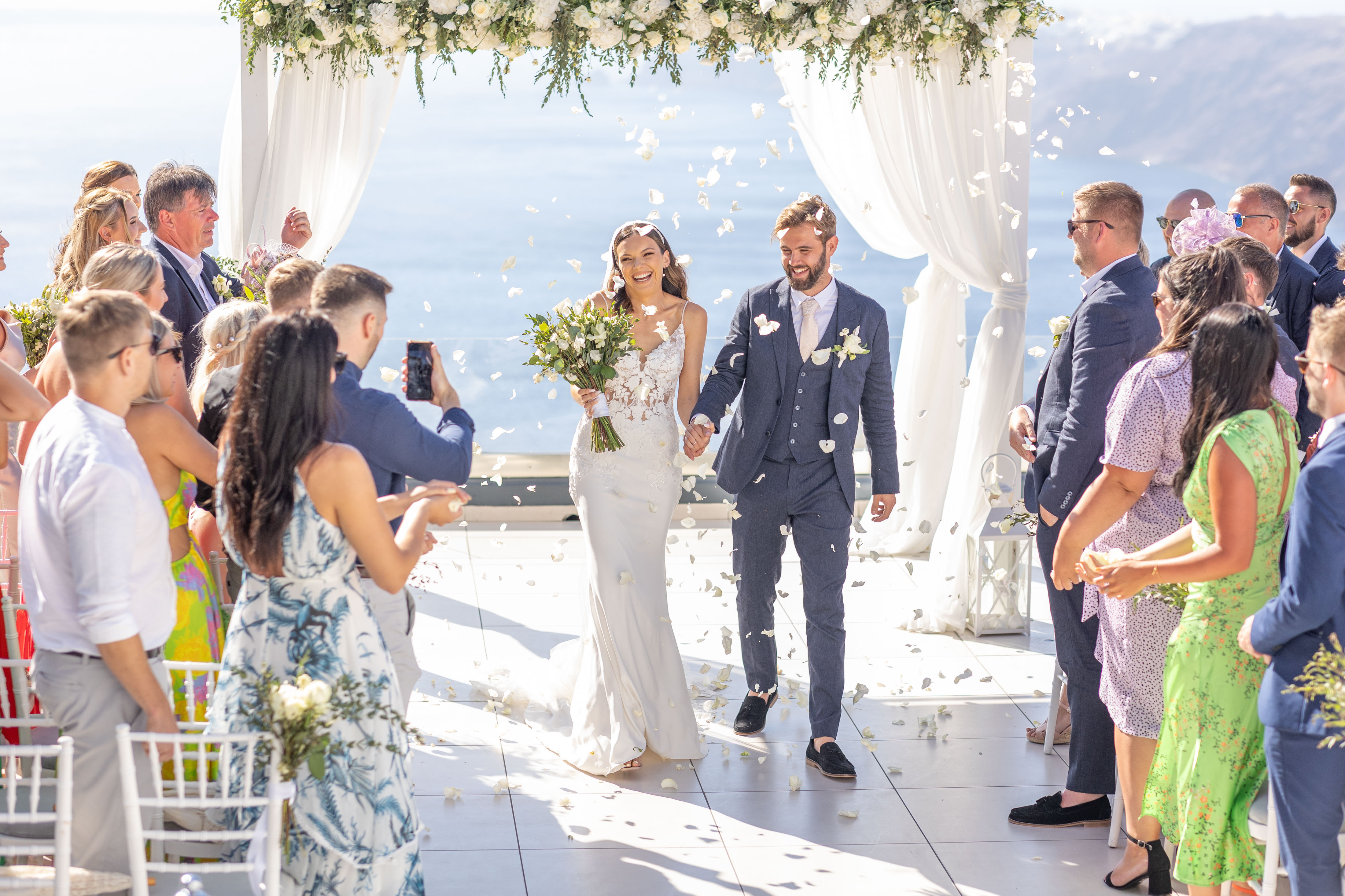 bride and groom covered in confetti at their wedding at Le Ciel Santorini