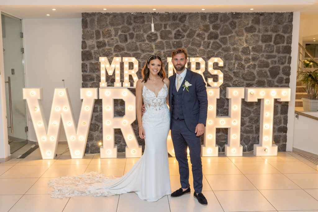 Bethan and Adam standing in front of light up letters