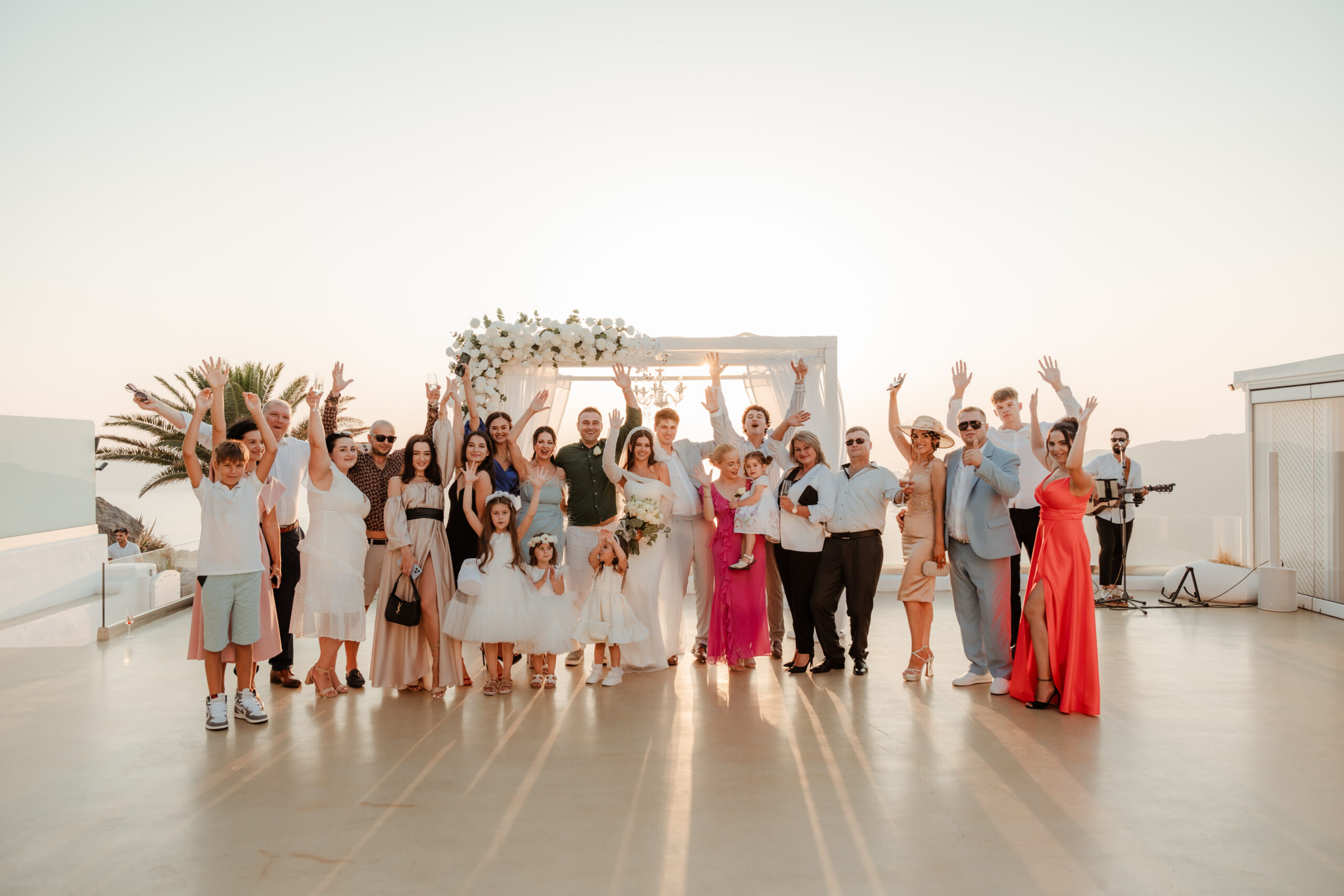 wedding group raising arms in the air at le Ciel wedding venue in Santorini