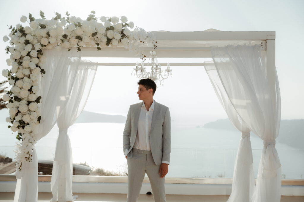 groom standing at Le Ciel Santorini in beige wedding suit
