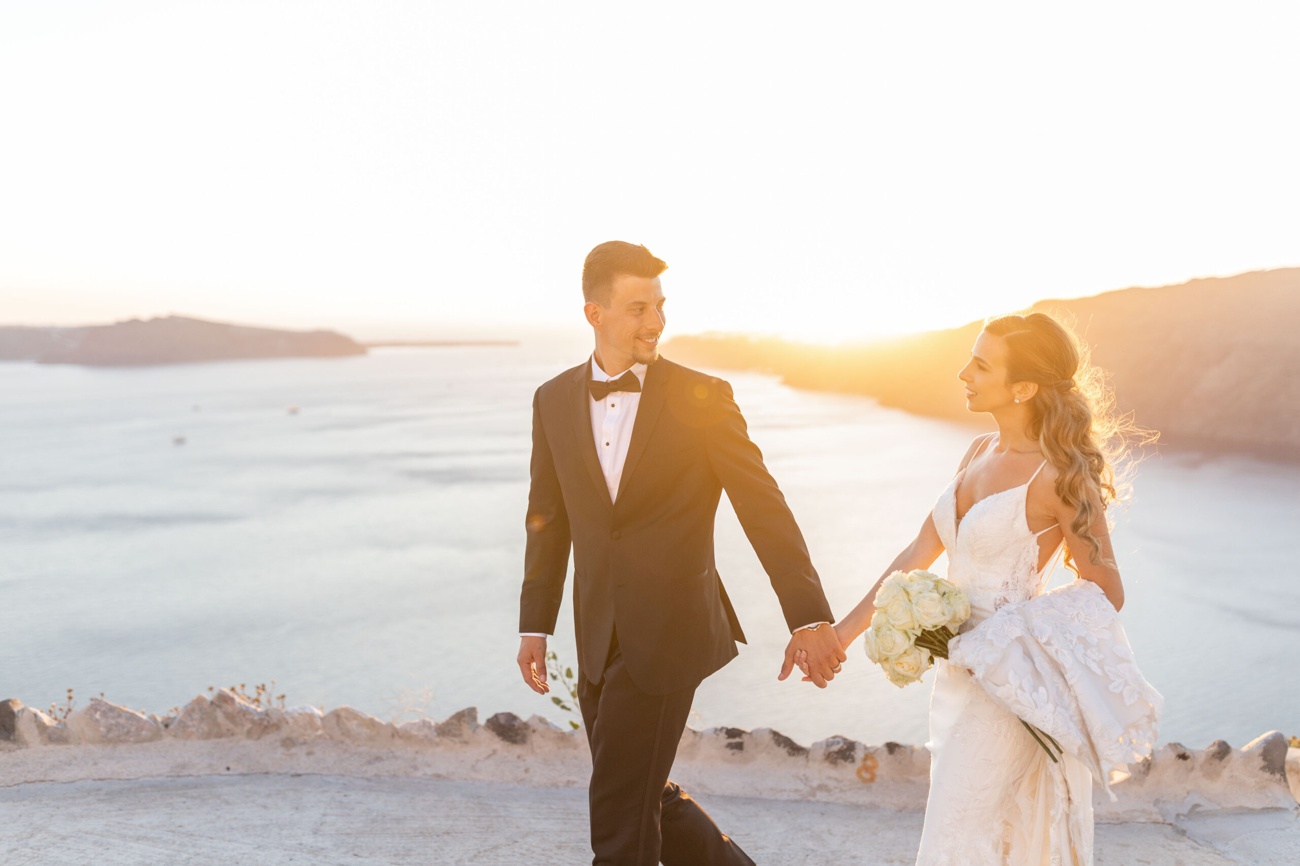 groom wearing tux holding brides hand in Santorini Le Ciel