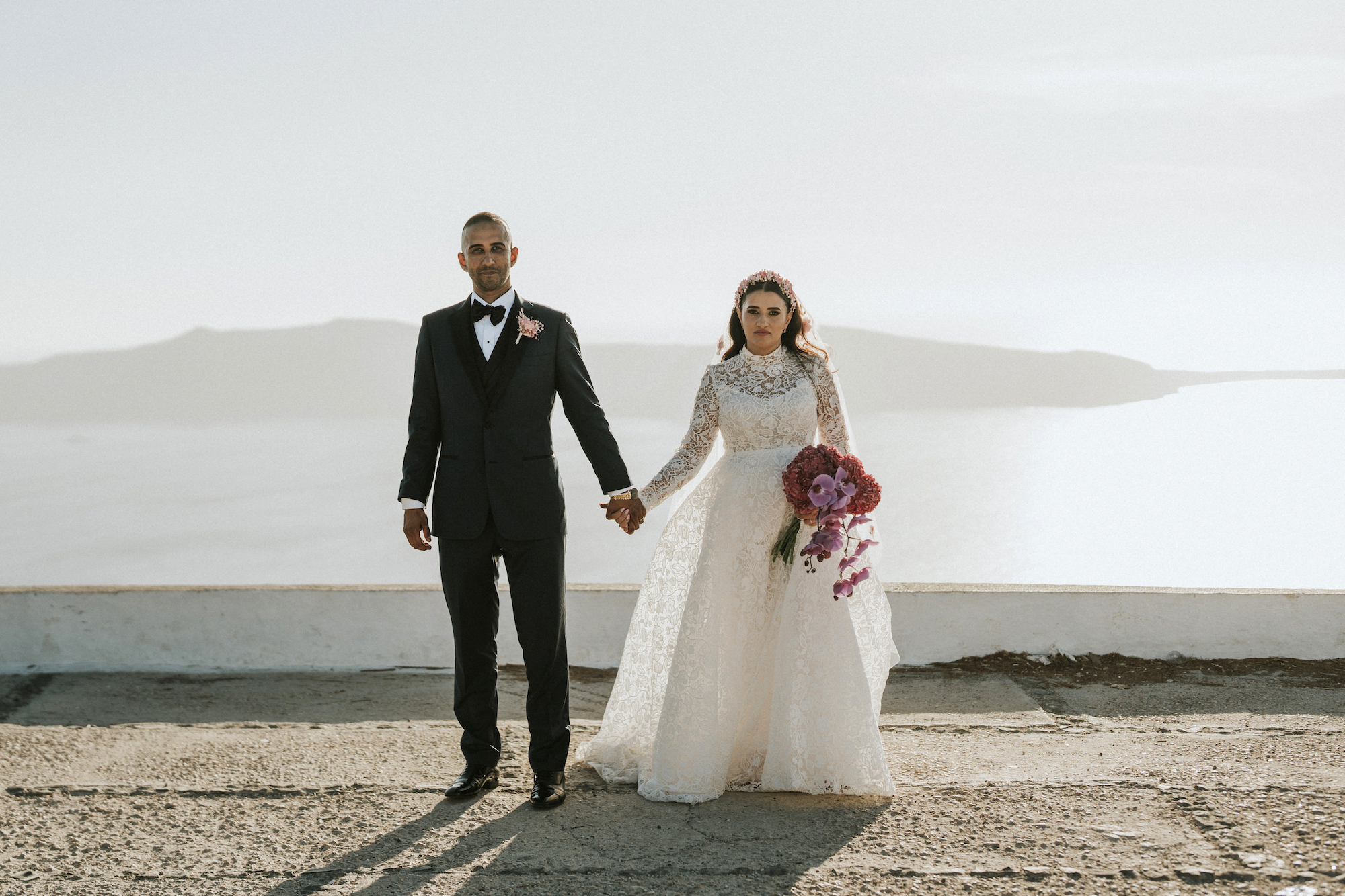 bride and groom standing in front of Santorini sea view