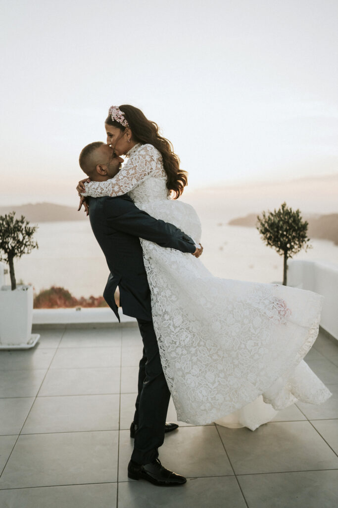 groom lifting up wife and kissing her in front of sunset
