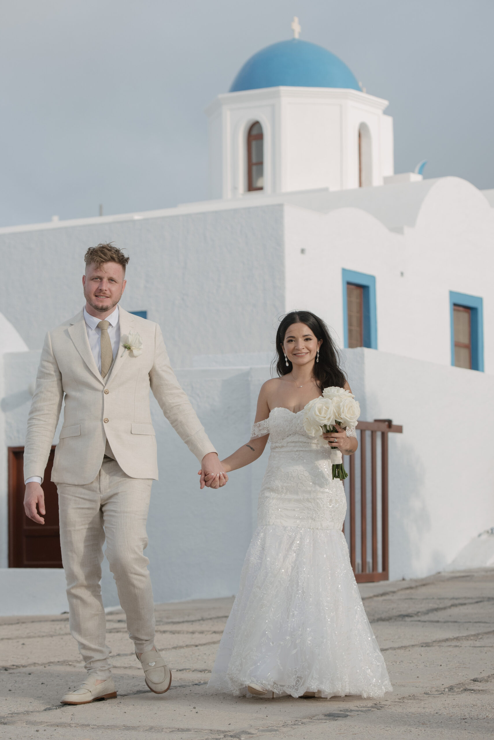 Carol and Jamie bride and groom walking past blue and white Greek building