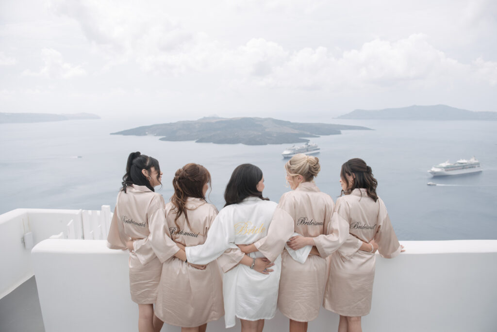 bride and bridesmaids facing out to Santorini coastline