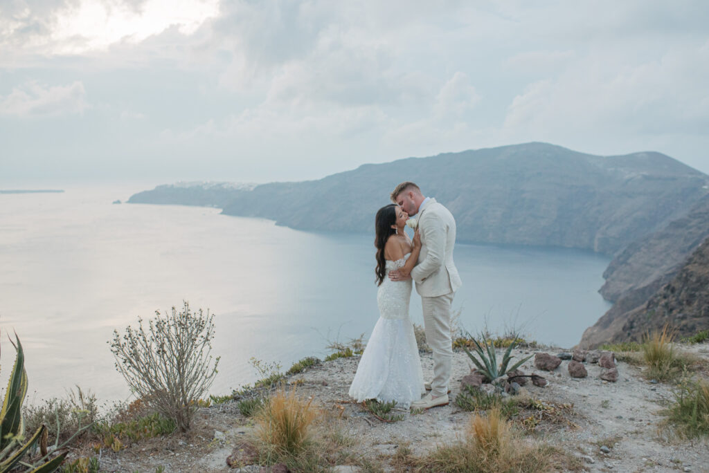 bride and groom kissing on a Santorini clifftop