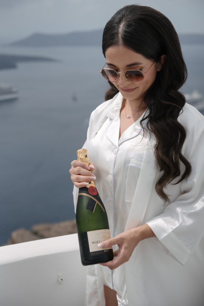 Carol the bride with a bottle of champagne at Santorini Le Ciel wedding venue