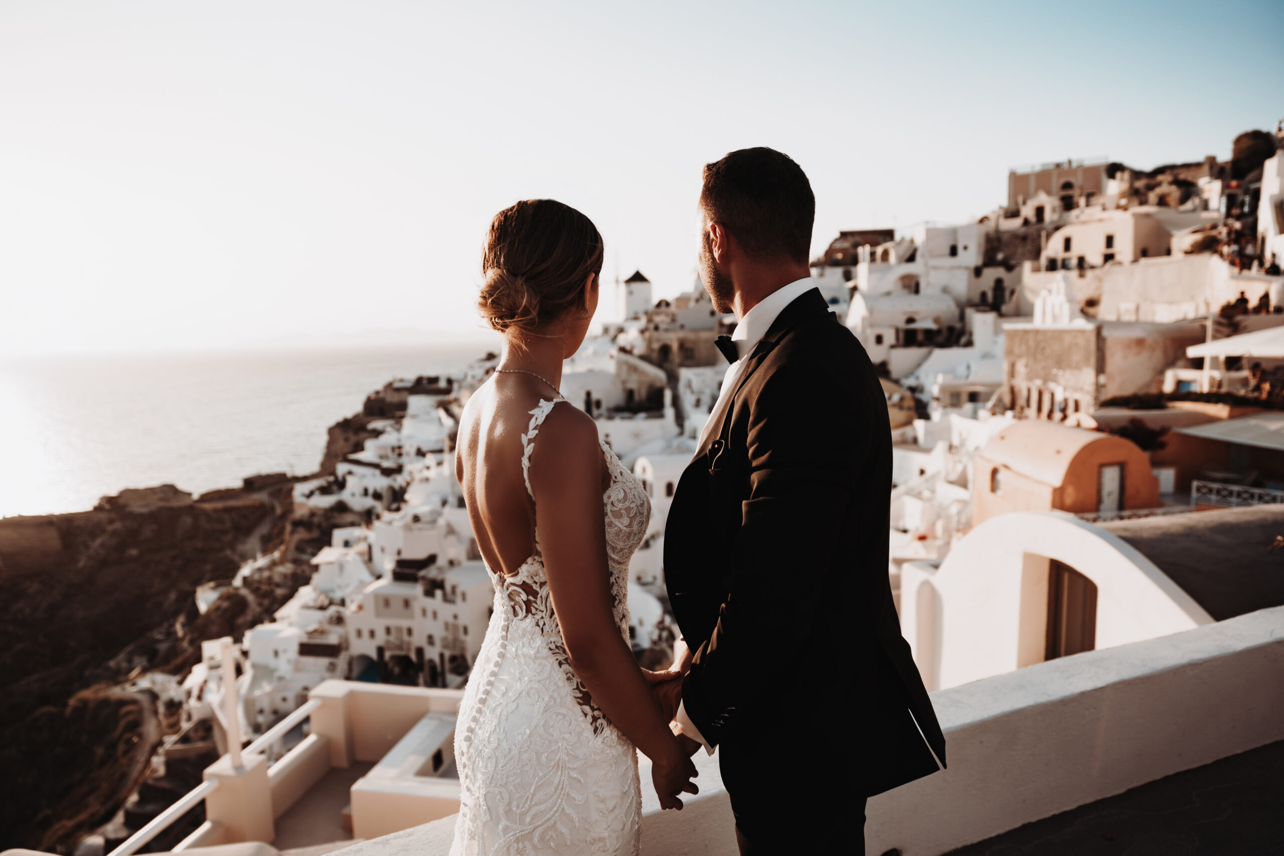 bride and groom looking out over Santorini