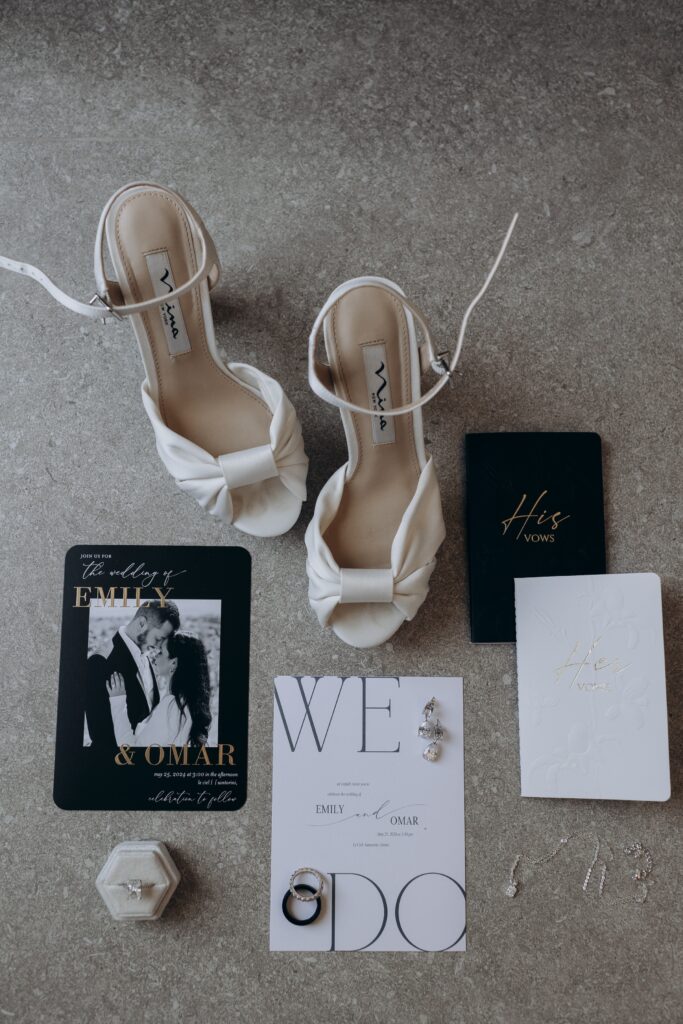 flatlay of wedding shoes, rings and invite