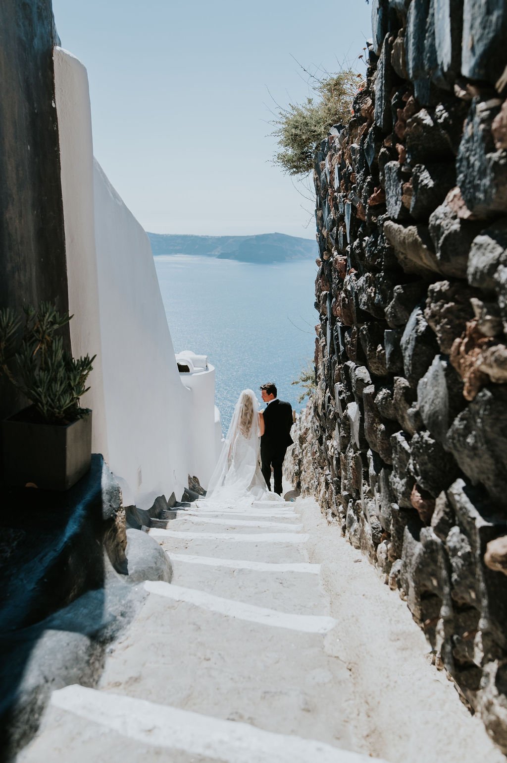 bride and groom walking down cobbled streets in Santorini