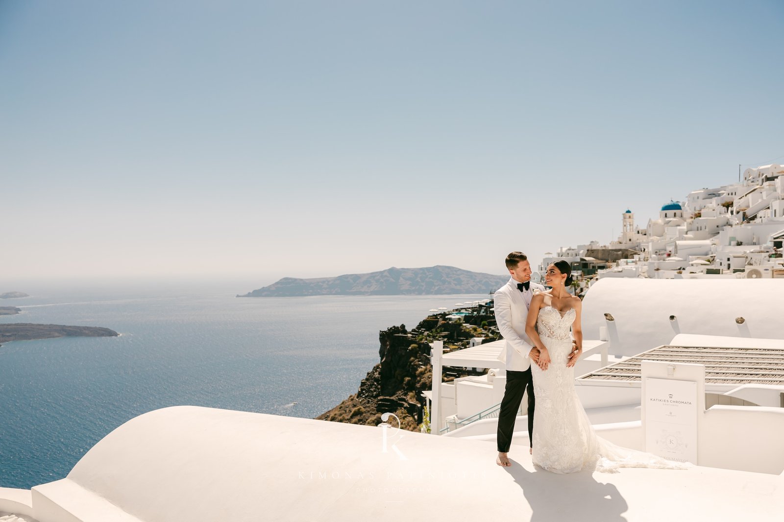 bride and groom with Santorini backdrop behind them